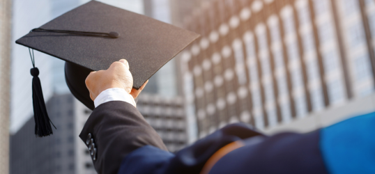 foto con studente di spalle che alza il cappello di laurea